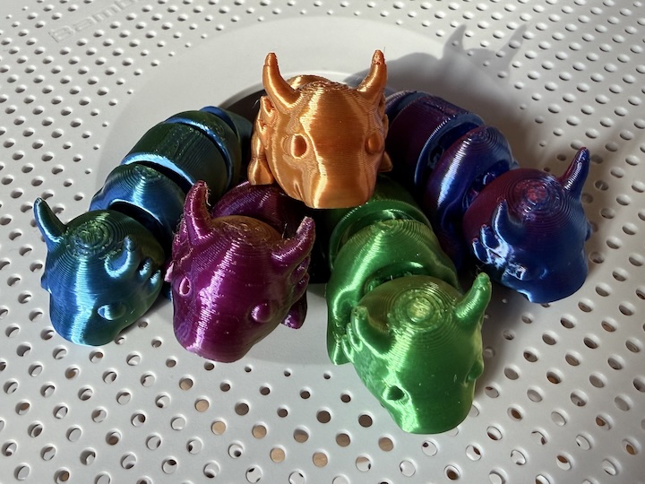 3D-printed articulated dragons, sitting in a spool